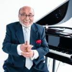 Portrait of Eddie Palmieri sitting in front of a grand piano