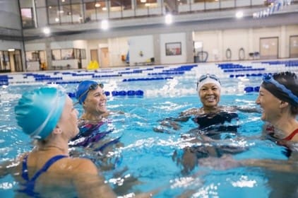 three women in an indoor pool wearing caps and goggles